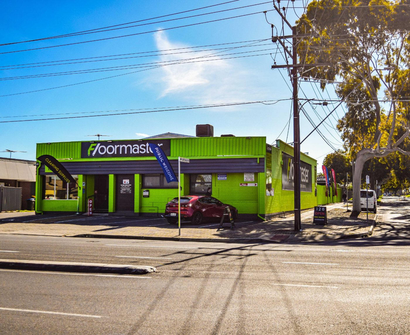 Floormaster cleaning supplies store on the corner of Floridale Road, Adelaide &ndash; bright green building with Public Welcome flags.